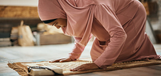  Une personne en train de prier sur un tapis de prière, avec un espace dédié et apaisant en arrière-plan.